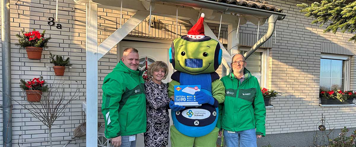 Das Maskottchen Teko, Stephan Masch (links) und Marco Schramm (rechts) überreichten die neue Fritzbox persönlich an Barbara Eller