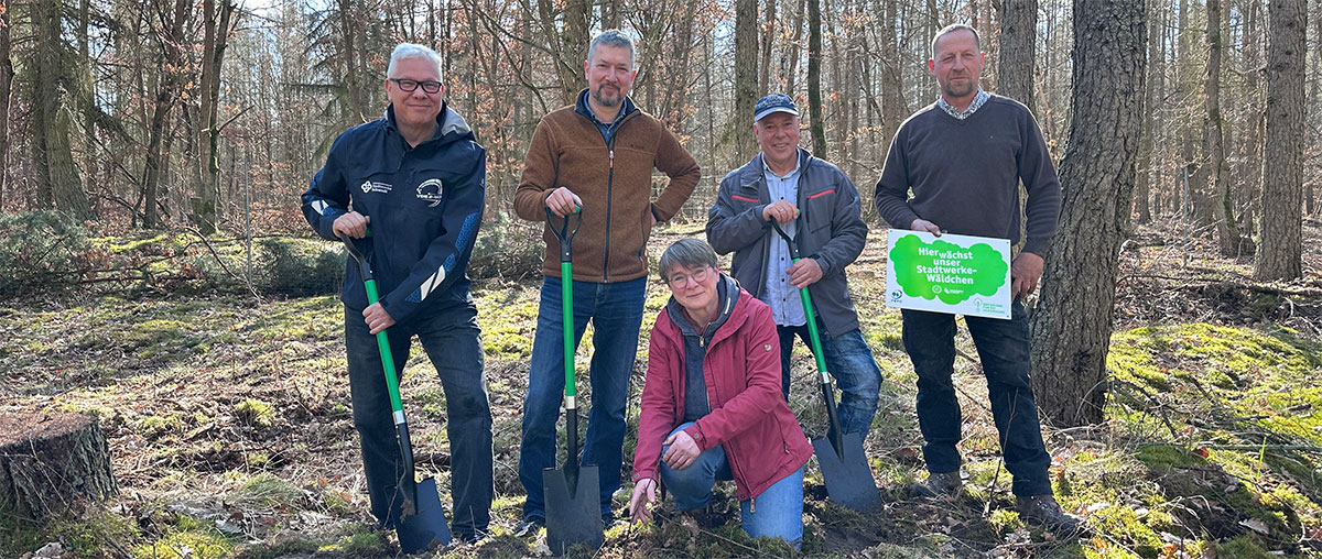 5 Personen im Wald beim Spatenstich für die Baumpflanzaktion