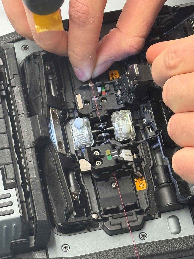 Mit einer Hand fädelt jemand Draht ein